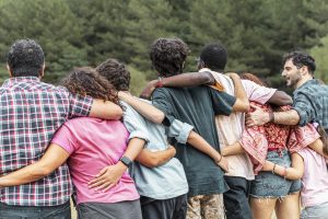 Group of diverse friends embracing each other outdoors, symbolizing unity, friendship, and connection. Concept of community, support, and togetherness.