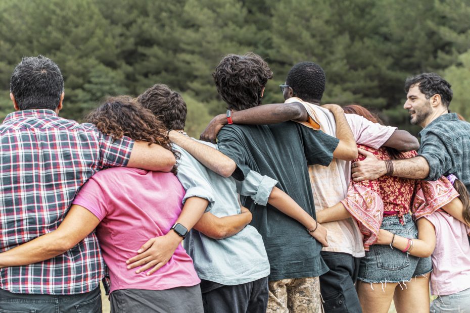 Group of diverse friends embracing each other outdoors, symbolizing unity, friendship, and connection. Concept of community, support, and togetherness.